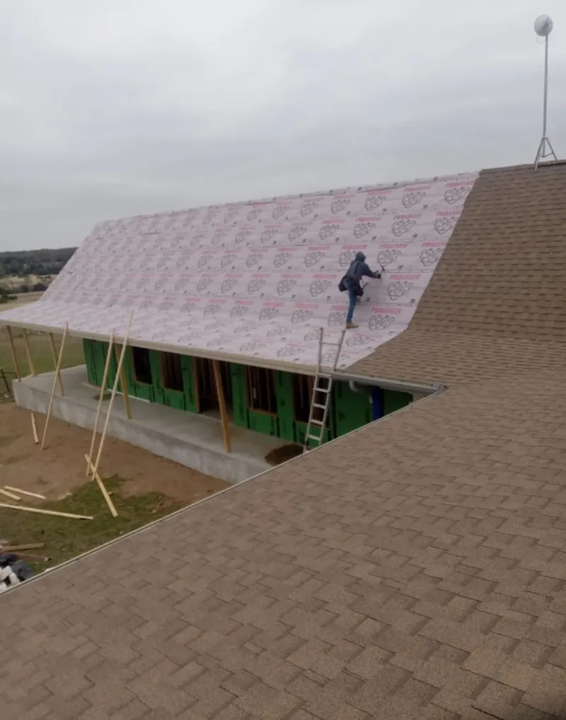 Worker preparing underlayment for a metal roof installation in Upper Providence